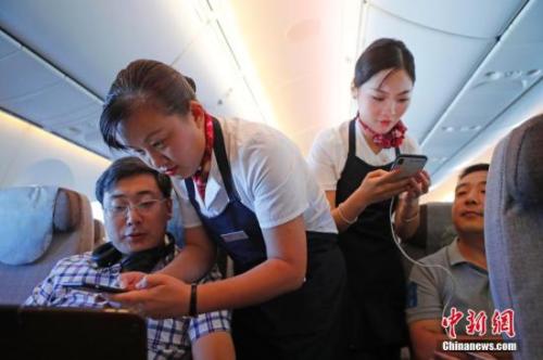 資料圖：乘務(wù)員們?cè)诳团搩?nèi)為旅客調(diào)試機(jī)上上網(wǎng)功能。<a target='_blank' ><p  align=